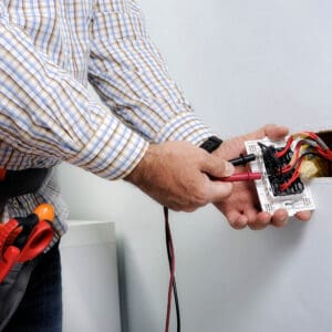 Electrician testing electrical outlet wiring.