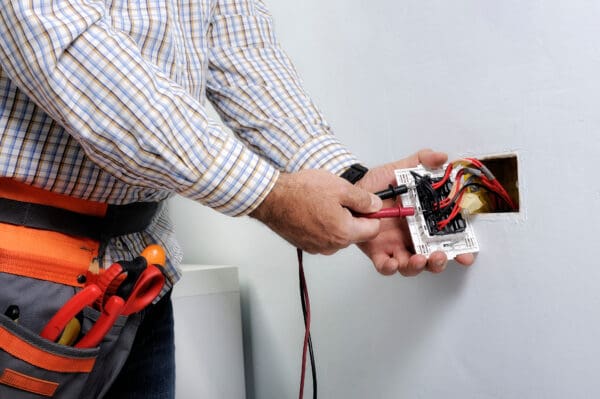 Electrician testing electrical outlet wiring.